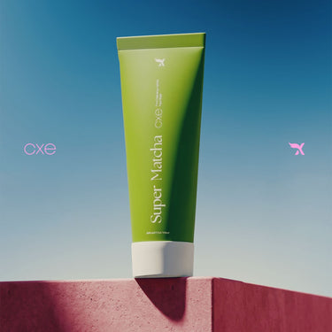 Green tube of Super Matcha product on a red surface with a blue sky background