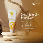 A tube of Vitamin C gel face wash displayed against a neutral background with a branch prop. The packaging is white with a yellow label, and the product is positioned in front of a light source, creating a shadow on the surface. XCosmetics | Cream X Emirates